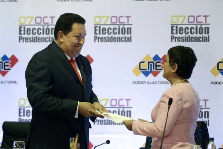 La presidenta del CNE, Tibisay Lucena, entrega a Hugo Chávez el acta que le acredita oficialmente como vencedor de las elecciones presidenciales de Venezuela. (Leo RAMÍREZ/AFP PHOTO)