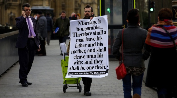 Un hombre protesta ante el Parlamento británico en la jornada en la que se ha aprobado el matrimonio ente homosexuales. (Andrew COWIE/AFP)