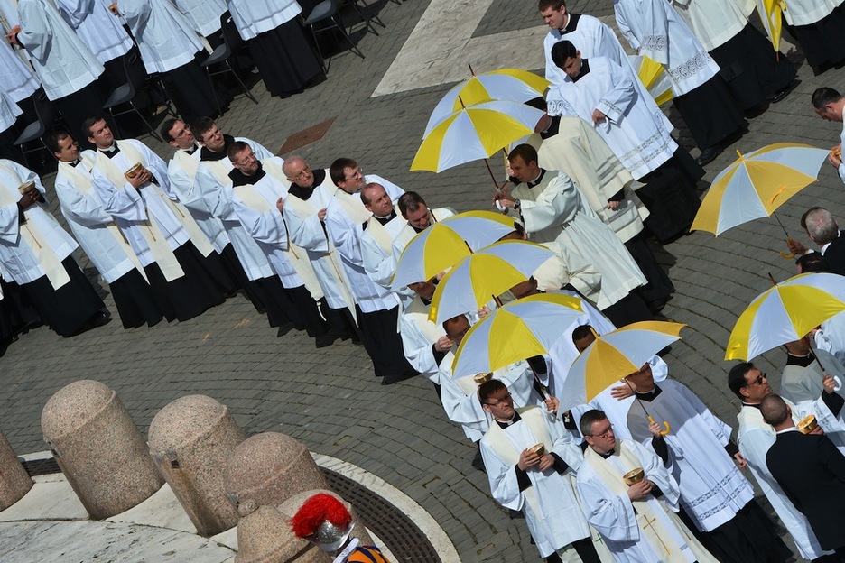 Los sacerdotes se protegen del sol con sombrillas. (Filippo MONTEFORTE/AFP)