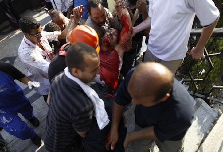 Varias personas trasladan a uno de los heridos en la movilización de los Hermanos Musulmanes. (Mahmud KHALED/AFP PHOTO)