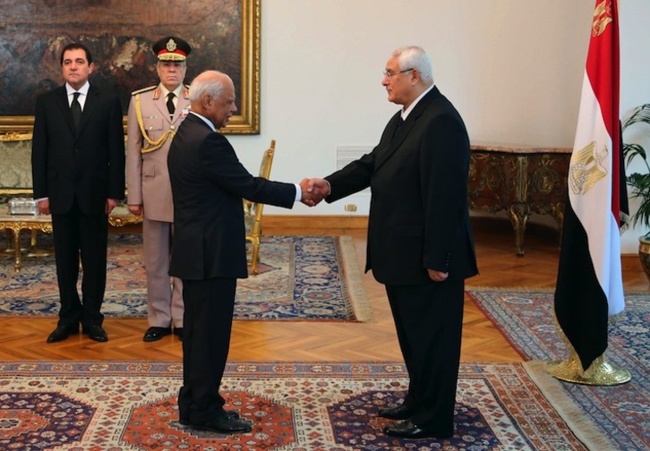 El primer ministro, Hazem el Beblaui (izda.) estrecha la mano del presidente interino, Adly Mansour. (AFP)