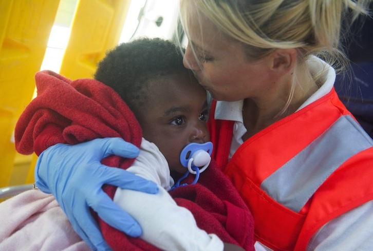 Una voluntaria de Cruz Roja besa a uno de los niños rescatados este fin de semana (Marcos MORENO / AFP PHOTO)