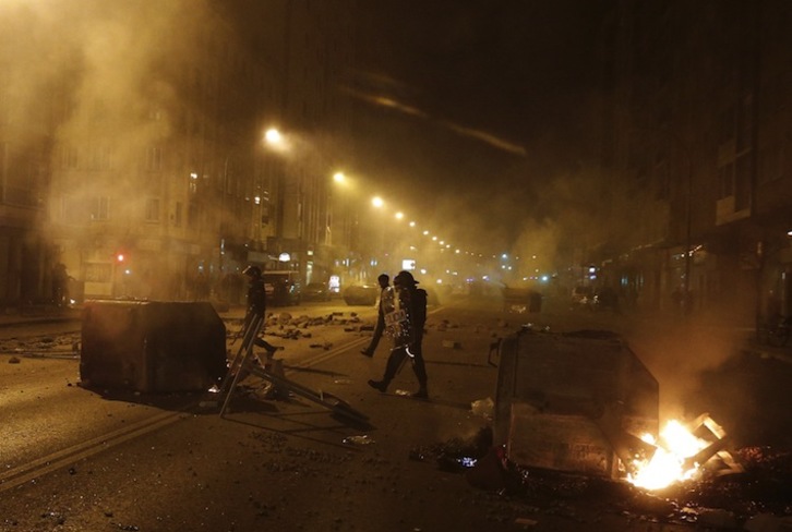 Policías caminando entre contenedores quemados. (César MANSO / AFP PHOTO)
