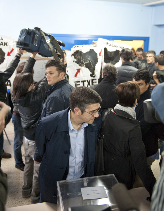 Patxi López, ante la urna, y al fondo la protesta contra la repatriación. (Jon HERNAEZ / ARGAZKI PRESS)