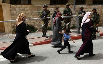 Mujeres palestinas pasan ante soldados israelíes de camino a la mezquita Ibrahimi en la ciudad de Hebrón.